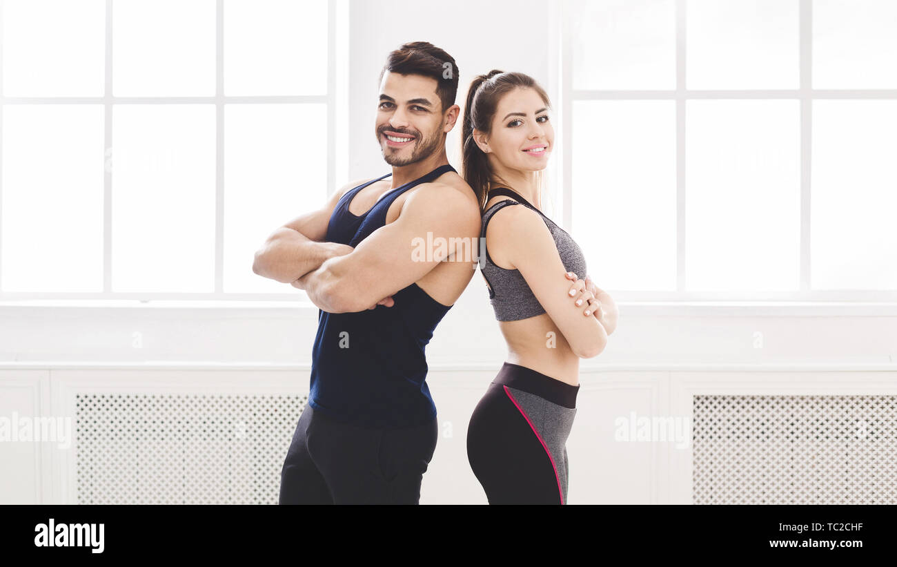 Successful couple standing back to back in studio with big windo Stock Photo
