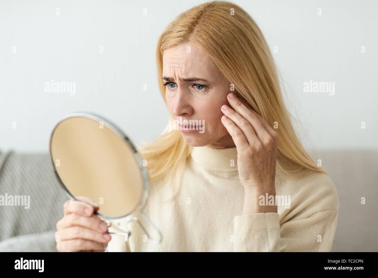 Anti-Wrinkle Skin Care. Sad Woman Looking In Mirror Stock Photo