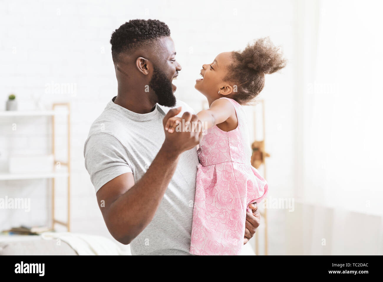 Cheerful black man dancing with his little daughter Stock Photo