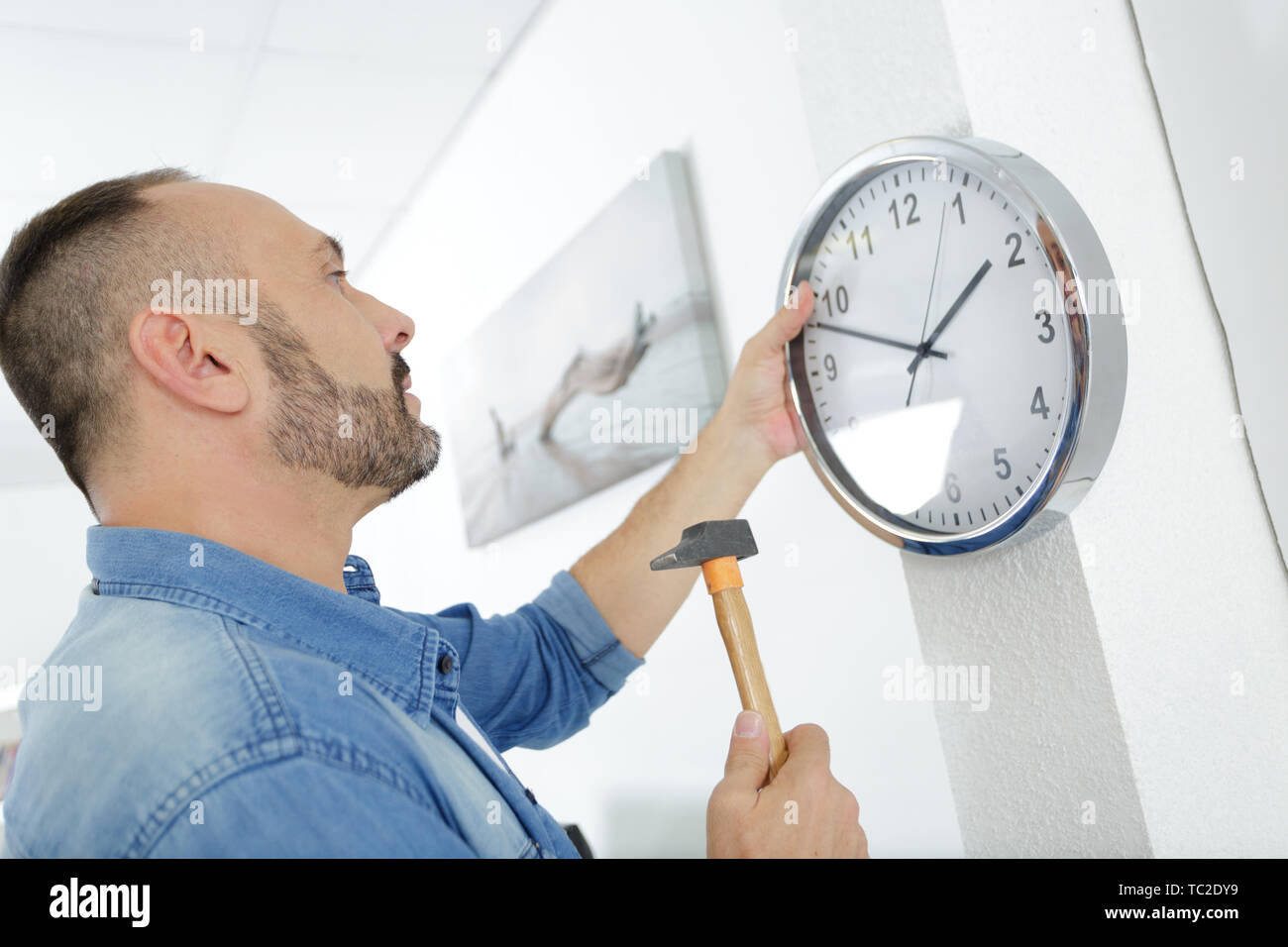 mature man fixing clock to the wall Stock Photo Alamy