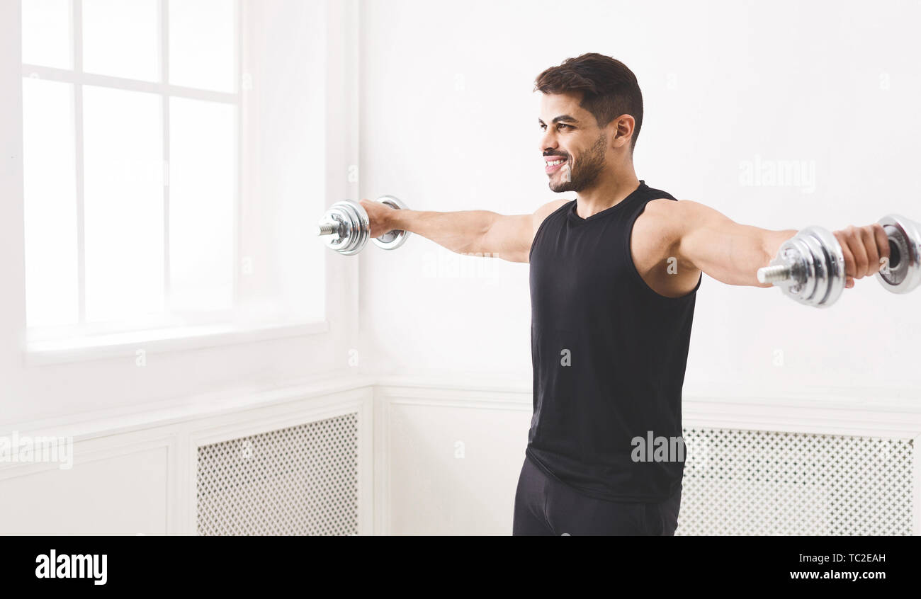 Young athlete man pumping his biceps with dumbbells Stock Photo - Alamy
