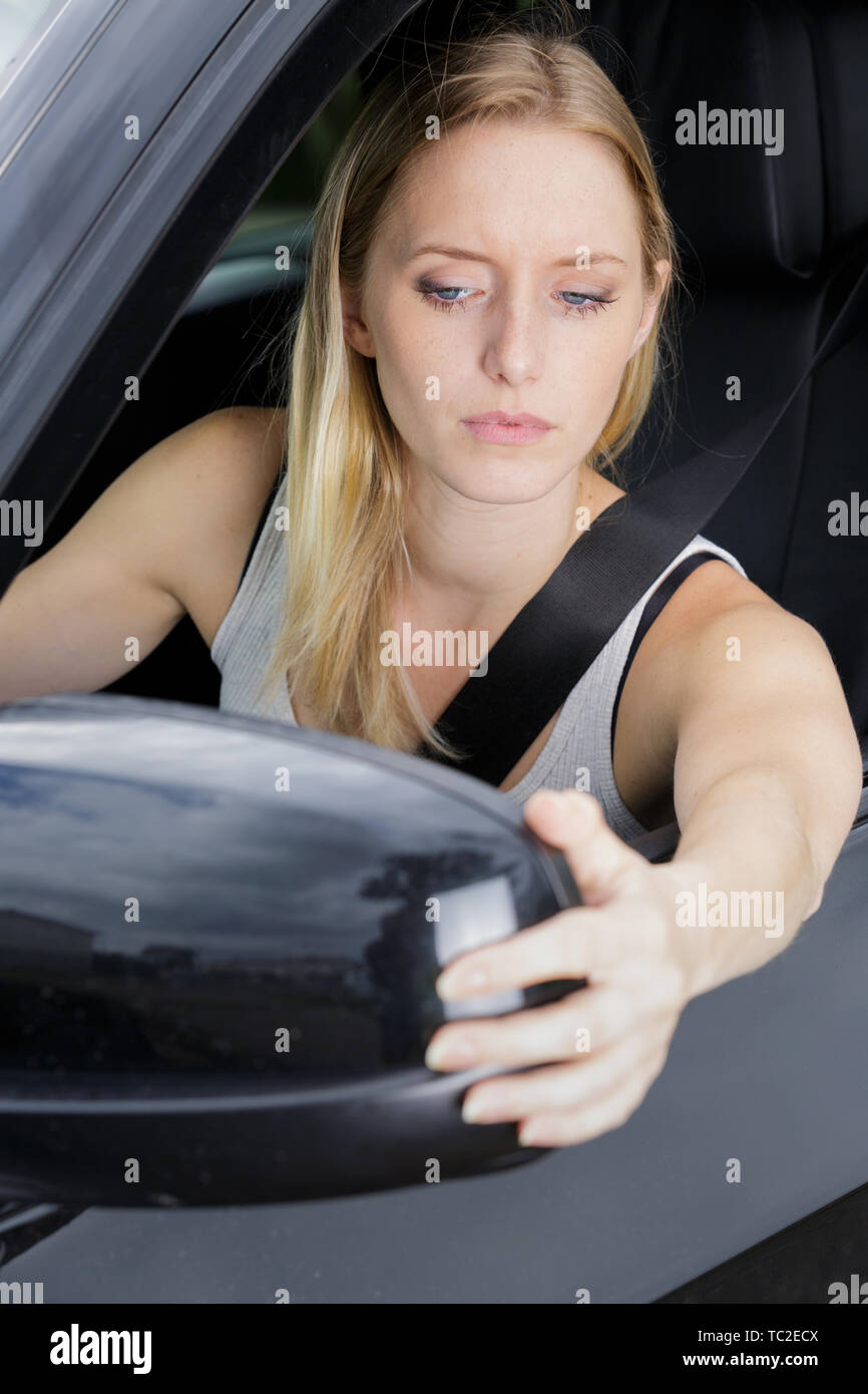 woman adjusting side mirror of blue car in nature Stock Photo Alamy