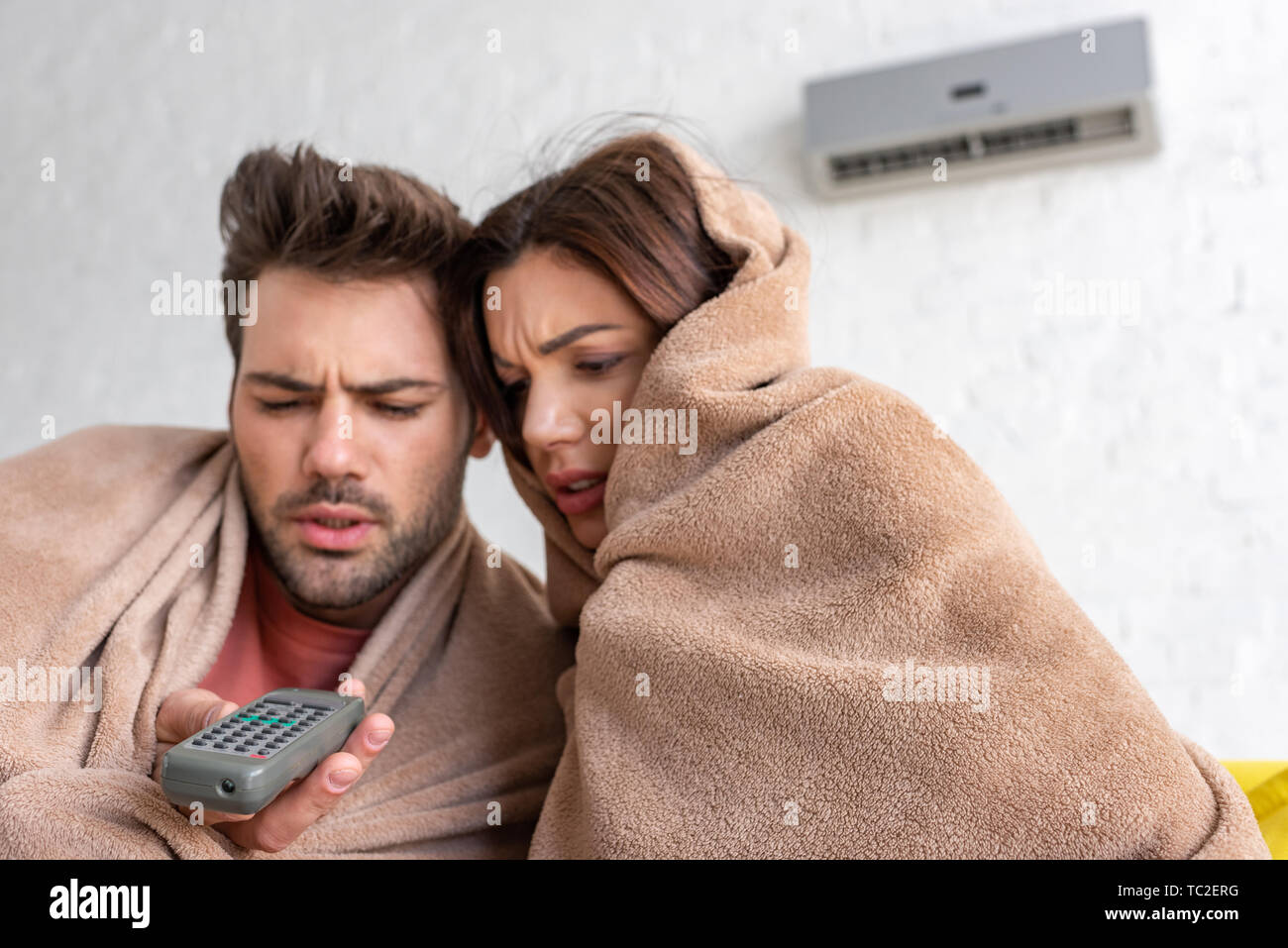 frozen couple warming under blankets while sitting under air