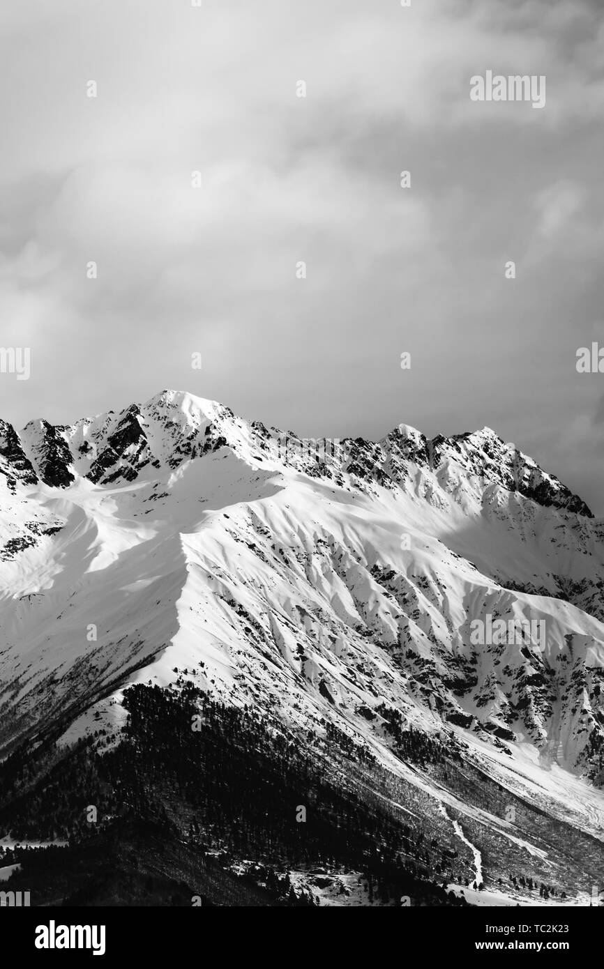 Snowy winter mountain and cloudy sky in evening. Caucasus Mountains, Svaneti region of Georgia. Black and white toned landscape. Stock Photo