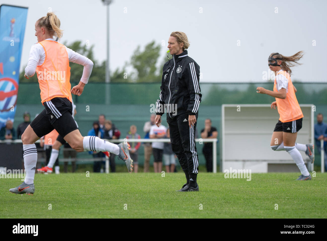 04 June 2019, France, Pont-Péan: Martina Voss-Tecklenburg (M), Trainerin  der deutschen Frauen-Nationalmannschaft, steht während einer  Trainingseinheit der deutschen Fußball-Nationalmannschaft der Frauen  zwischen zwei Spielerinnen. Photo: Sebastian ...