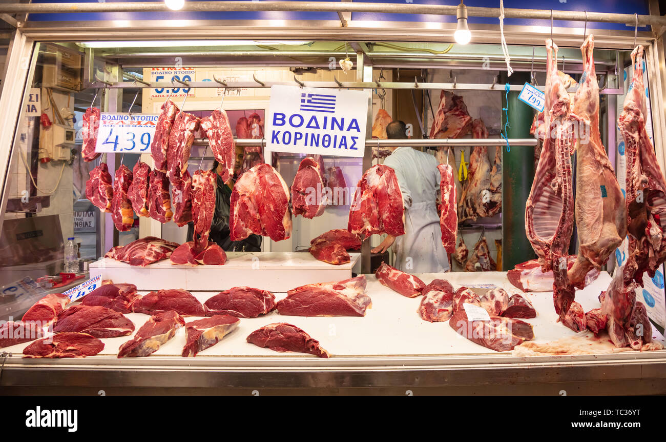 April 28, 2019. Athens, Greece. Raw beef in a row out of a butcher shop. Cow meat in big pieces hangs from hook ready to be sold. Store background. Stock Photo