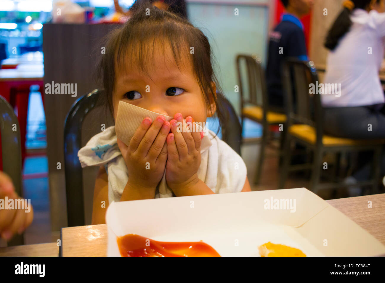 CHIANGMAI,THAILAND-MAY 3,2019 : Little Child eating fried chicken in the background of KFC restaurant. Stock Photo