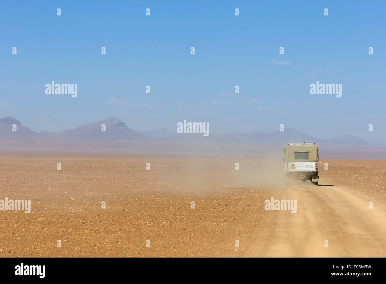 4x4 vehicle travelling on a dusty gravel track in desert landscape, Kaokoveld, Namibia Stock
