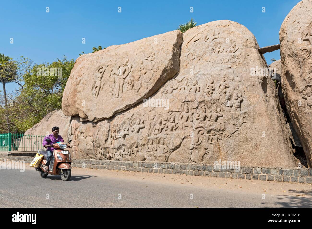 Man on motorcycle in front of unfinished stone relief Carving, Mahabalipuram, Mamallapuram, India Stock Photo
