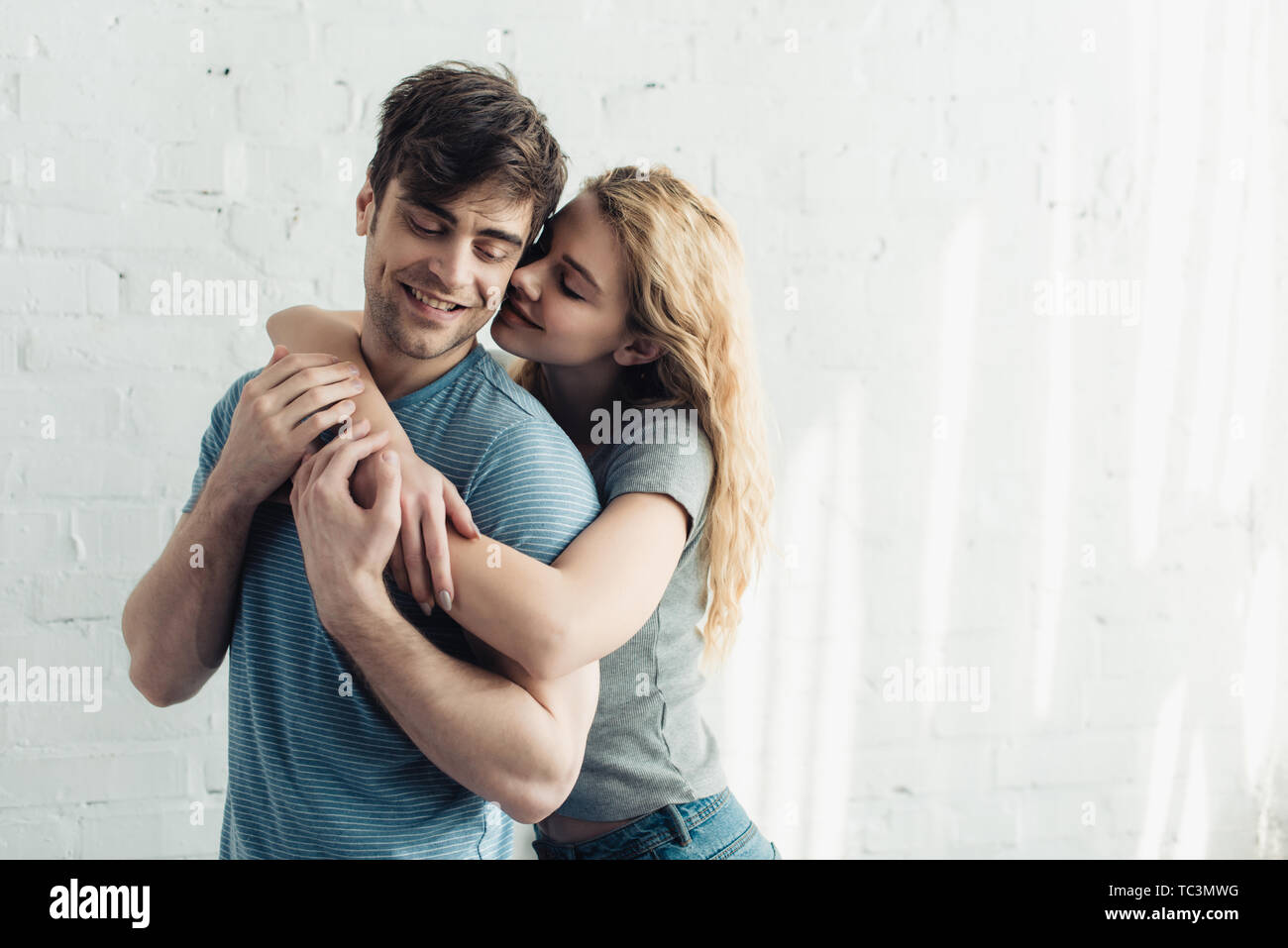 blonde cheerful girl hugging handsome and happy boyfriend Stock Photo ...