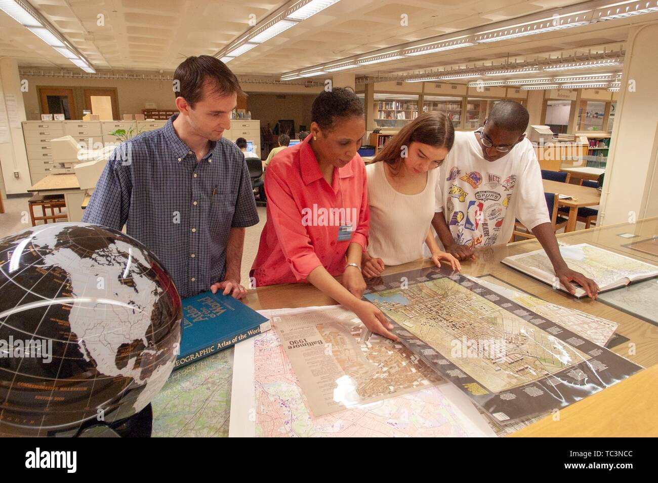 Librarian Sharon Morris helps patrons view a collection of maps in the Milton S Eisenhower Library at the Johns Hopkins University, Baltimore, Maryland, July 21, 2004. From the Homewood Photography Collection. () Stock Photo