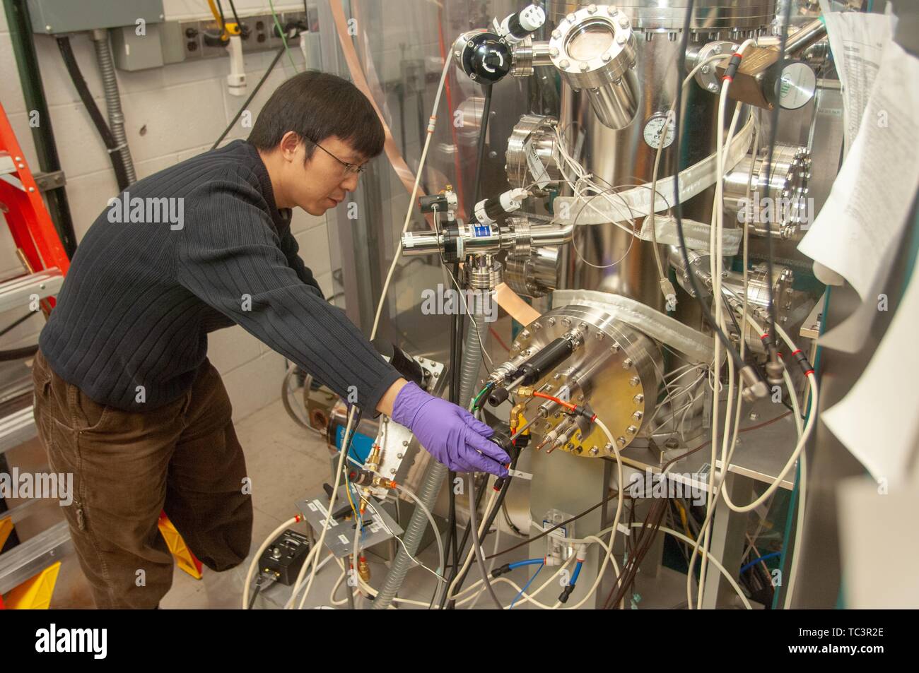 A researcher bends over to adjust equipment in a Physics and Astronomy lab room at the Johns Hopkins University, Baltimore, Maryland, February 9, 2007. From the Homewood Photography Collection. () Stock Photo