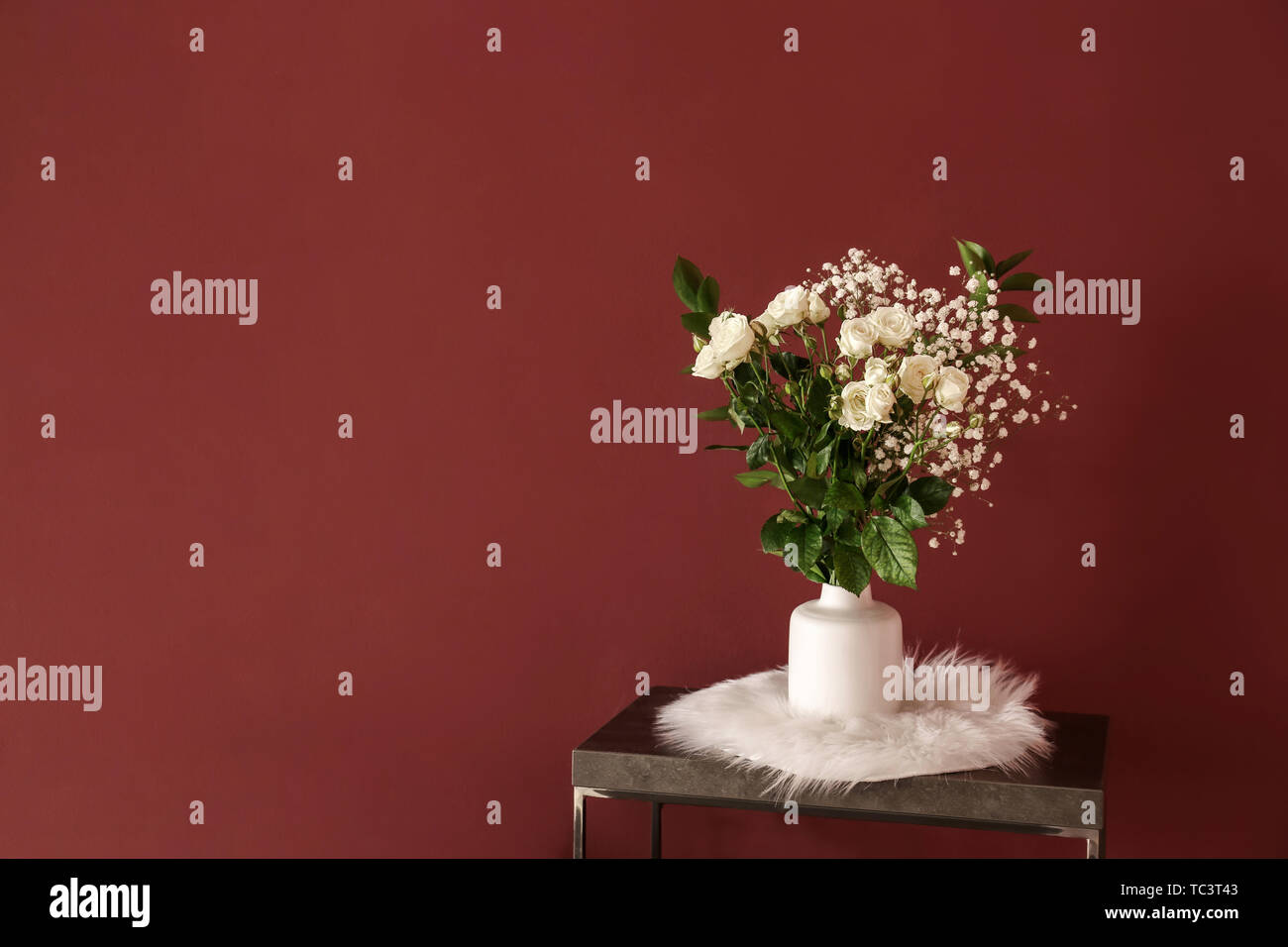 Table with flowers in vase near color wall Stock Photo - Alamy