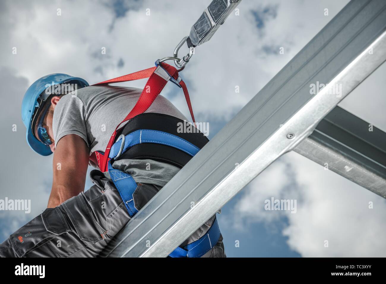 Safety Harness Equipment. Caucasian Contractor in His 30s on a Steel Building Frame. Shock Absorbing Lanyard Stock Photo