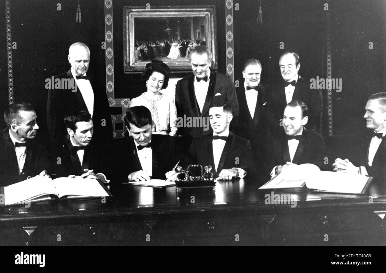 Apollo 7 and 8 flight crews signing a commemorative document to be hung in the Treaty Room of the White House, Washington, District of Columbia, with dignitaries looking on, December 3, 1968. Image courtesy National Aeronautics and Space Administration (NASA). () Stock Photo