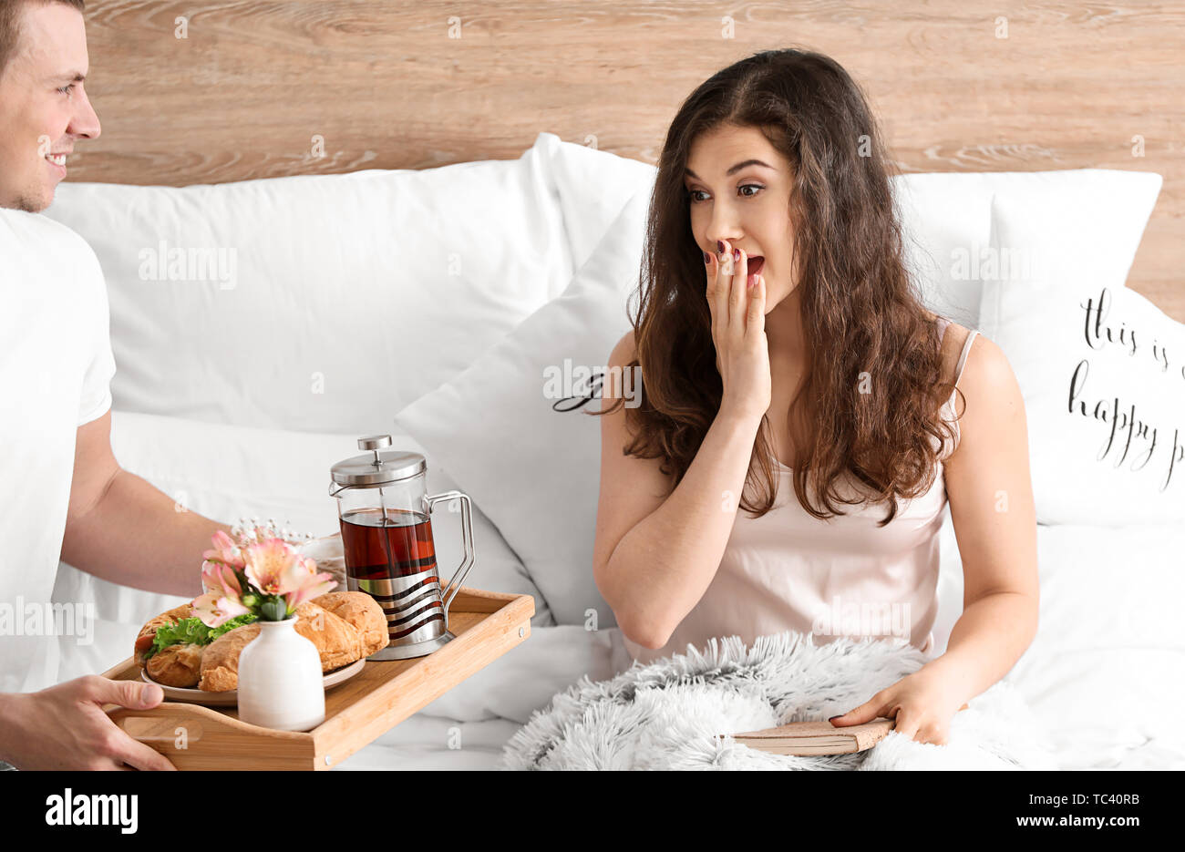 Young woman receiving breakfast in bed from her beloved husband Stock