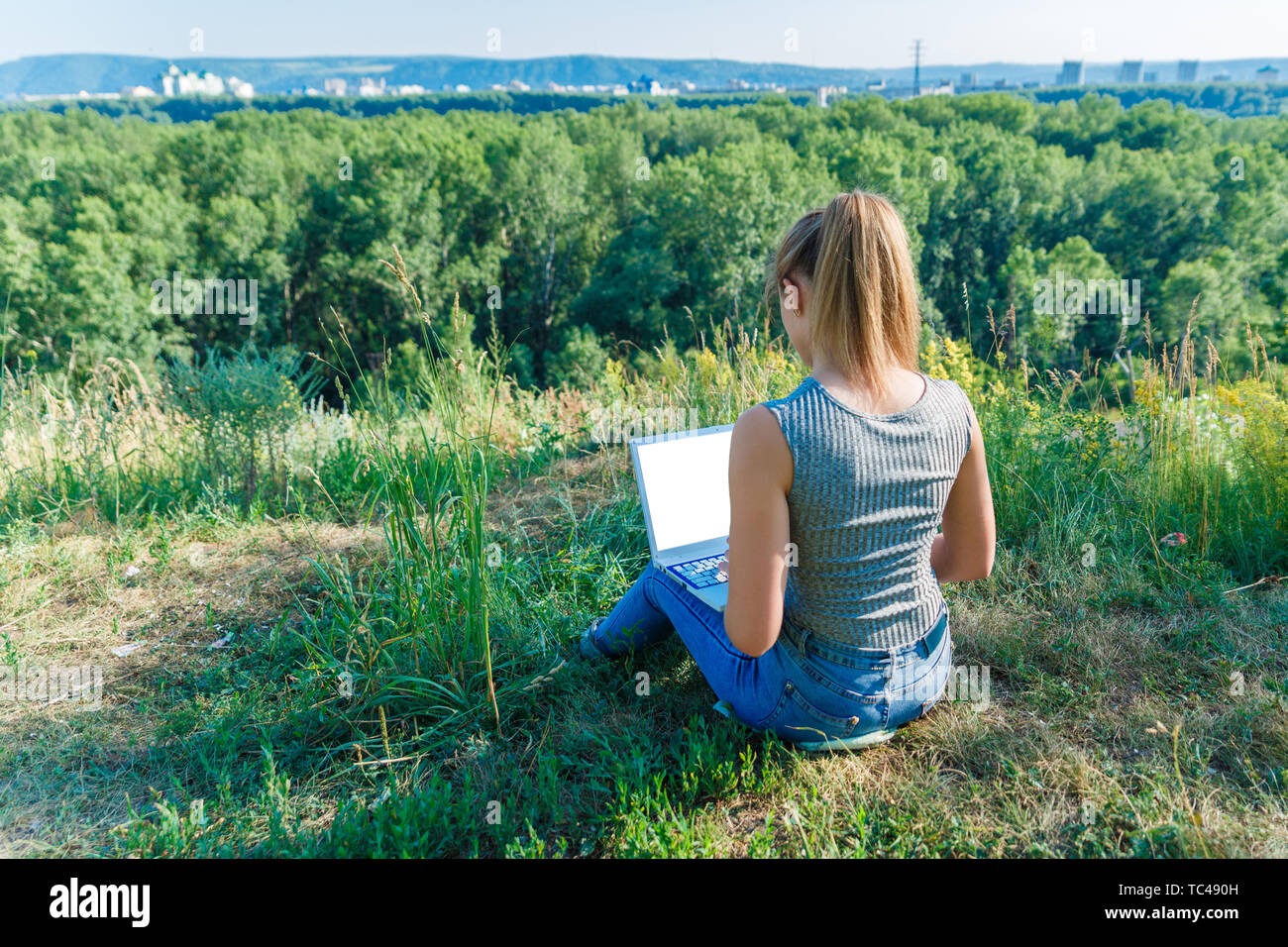 Girl with laptop on the nature on the background of forest and sky. The  concept of combining leisure and work. Individual entrepreneur Stock Photo  - Alamy