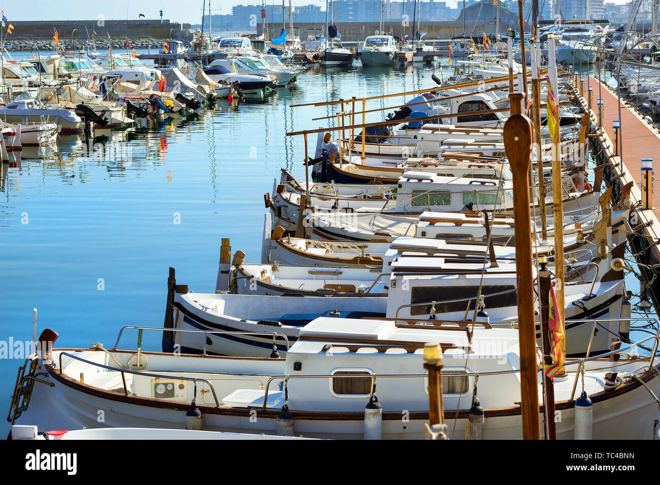 Private yachts and fishing boats moored at pier in seaport Blanes. Sailing and motor boats are moored at seawall. Vessels with catch of sea fish delicacies. Marina Blanes, Spain, Costa Brava Stock Photo
