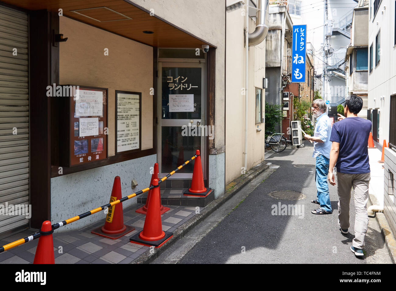 Two men look at the newly closed Jakotsu-yu (Jakotsuyu) hot spring in the Asakusa neighborhood of Tokyo, out of business since 31 May 2019. Stock Photo