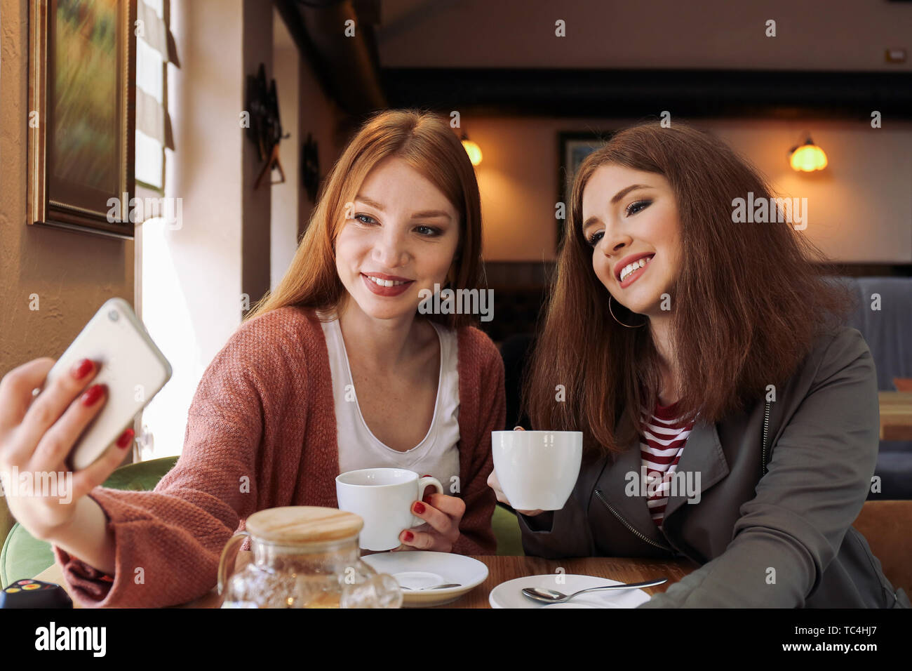 Beautiful young women taking selfie in cafe Stock Photo - Alamy