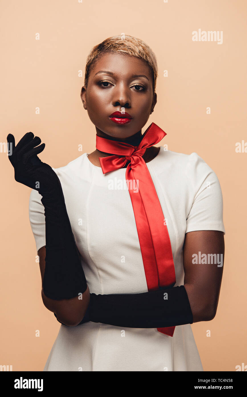 young african american woman posing in white dress, red scarf and black  gloves isolated on beige Stock Photo - Alamy