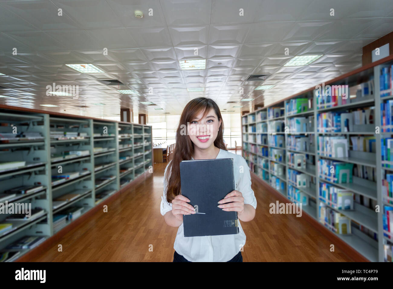 Asian beautiful female student holding book in library Stock Photo - Alamy