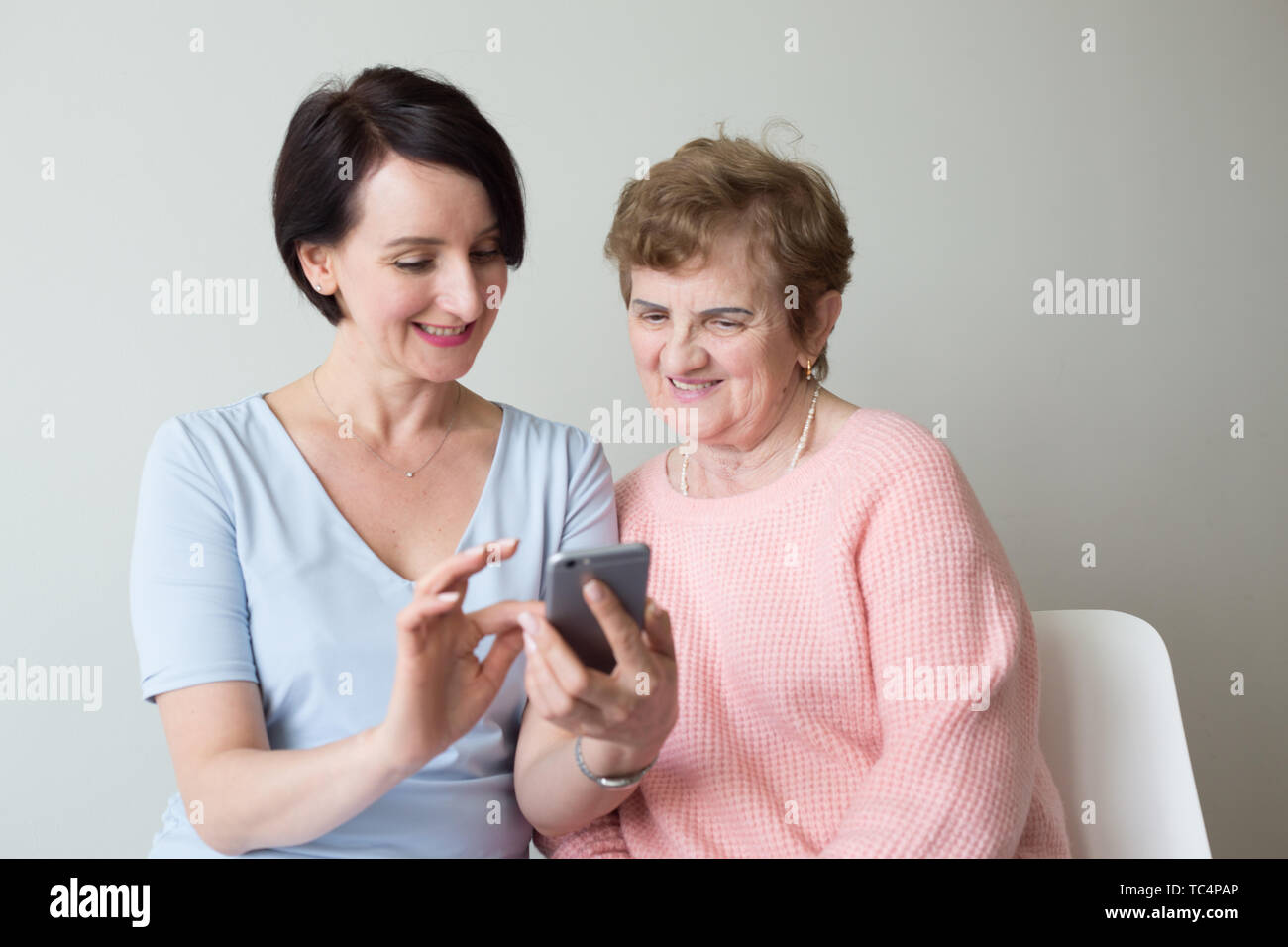 Young woman helping older female using smartphone Stock Photo