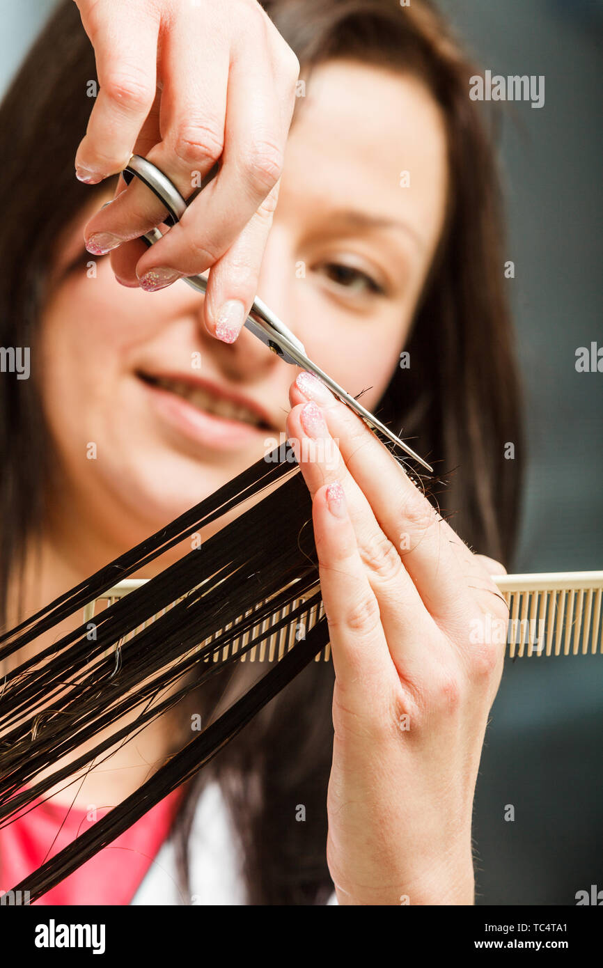 Hairdresser cutting dark hair using professional scissors, taking care