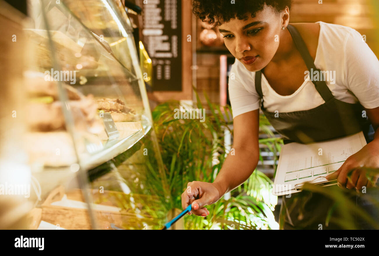 Female cafe owner checking stock and making notes looking at the ...