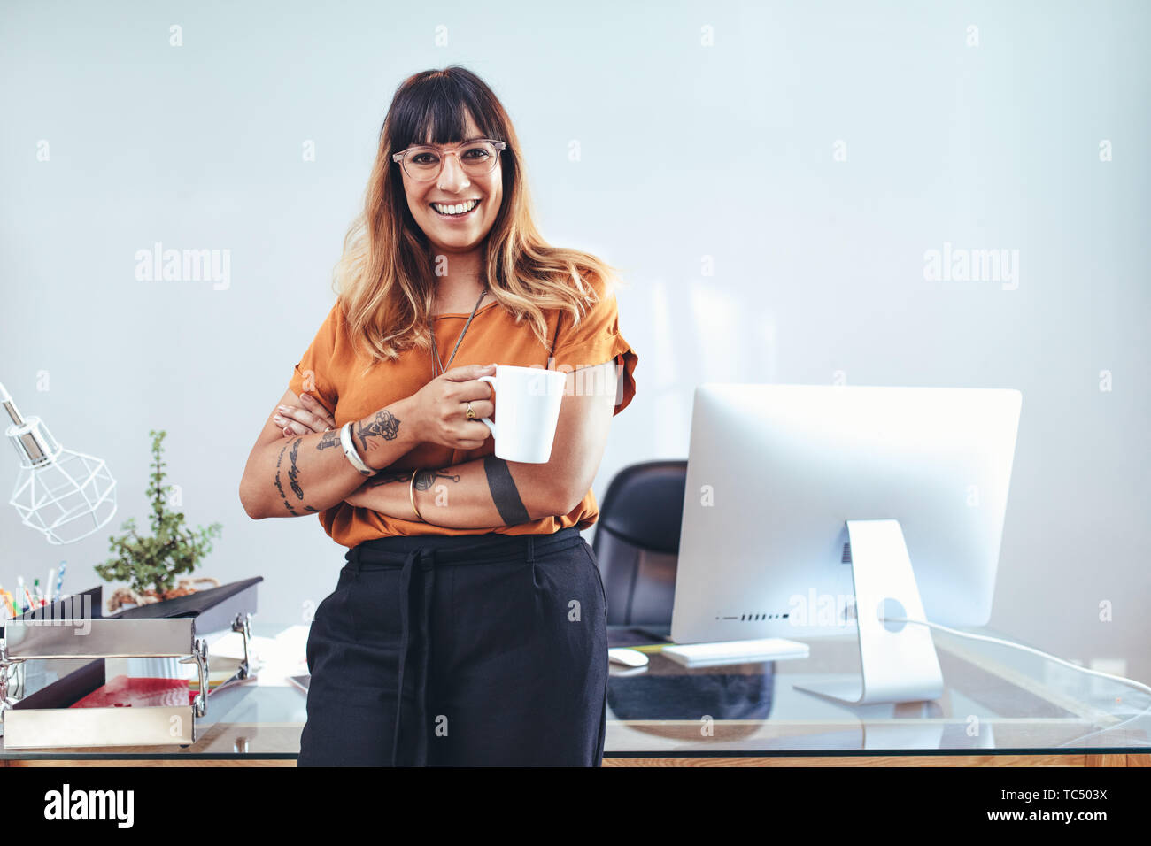 Smiling businesswoman standing with a coffee cup in hand. Portrait of a ...