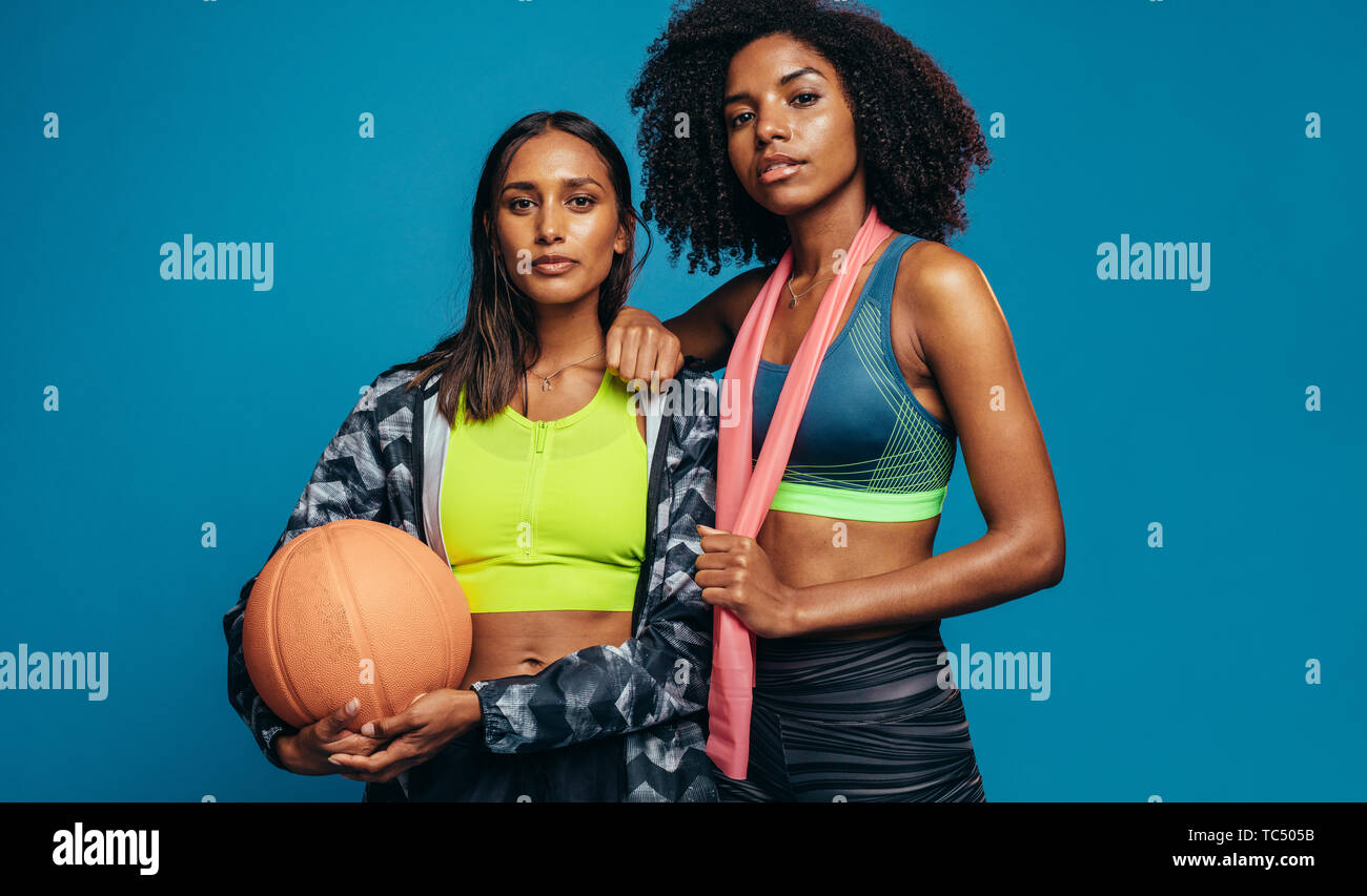 Three fitness young girls in sportswear standing against wall in fitness  gym. Girls smiling and looking to the camera Stock Photo - Alamy
