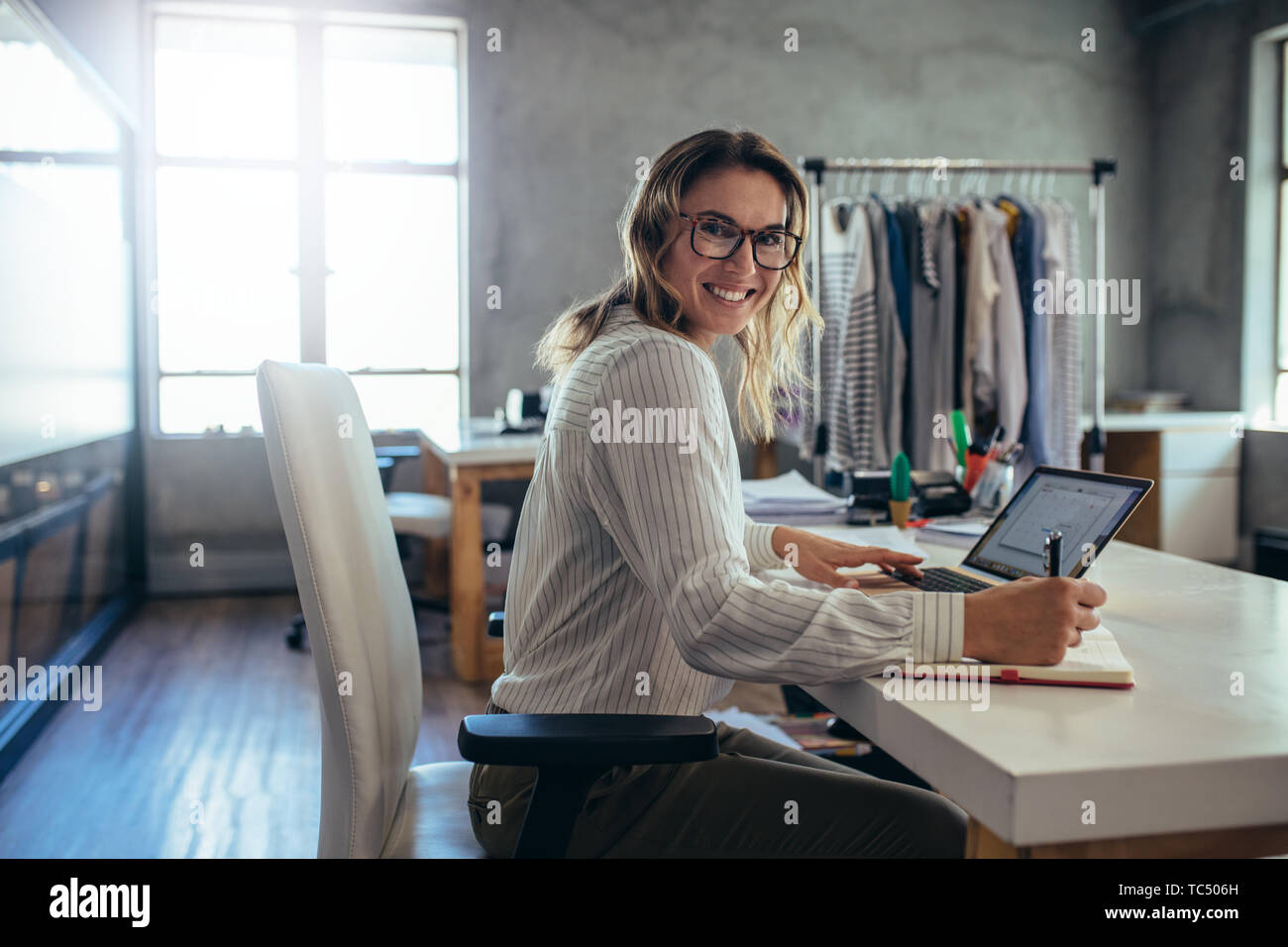 Happy woman business owner writing notes in diary. Online store working at her desk. Stock Photo