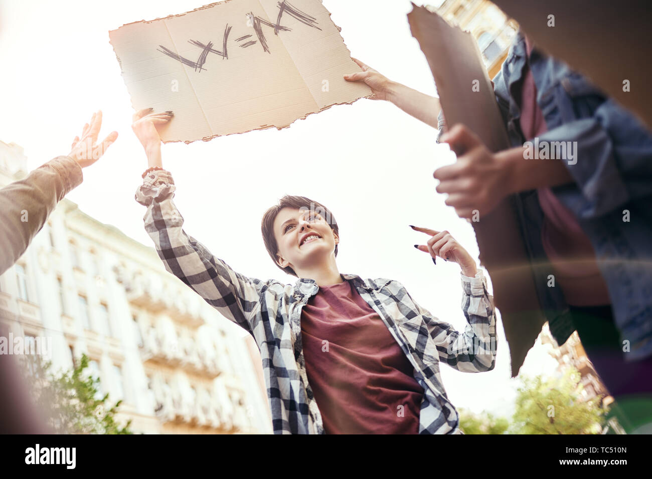 Women's march. Group of happy and young female activists protesting for equality on the road and holding a signboard with word w m. Women rights. Human rights. Women empowerment Stock Photo