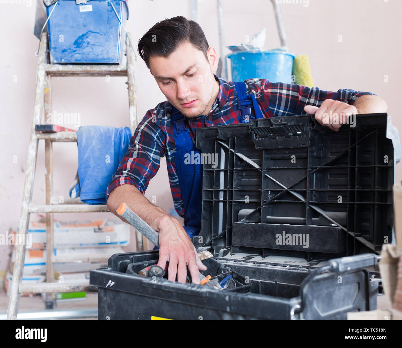 Young builder handyman choosing necessary tool in toolbox Stock Photo