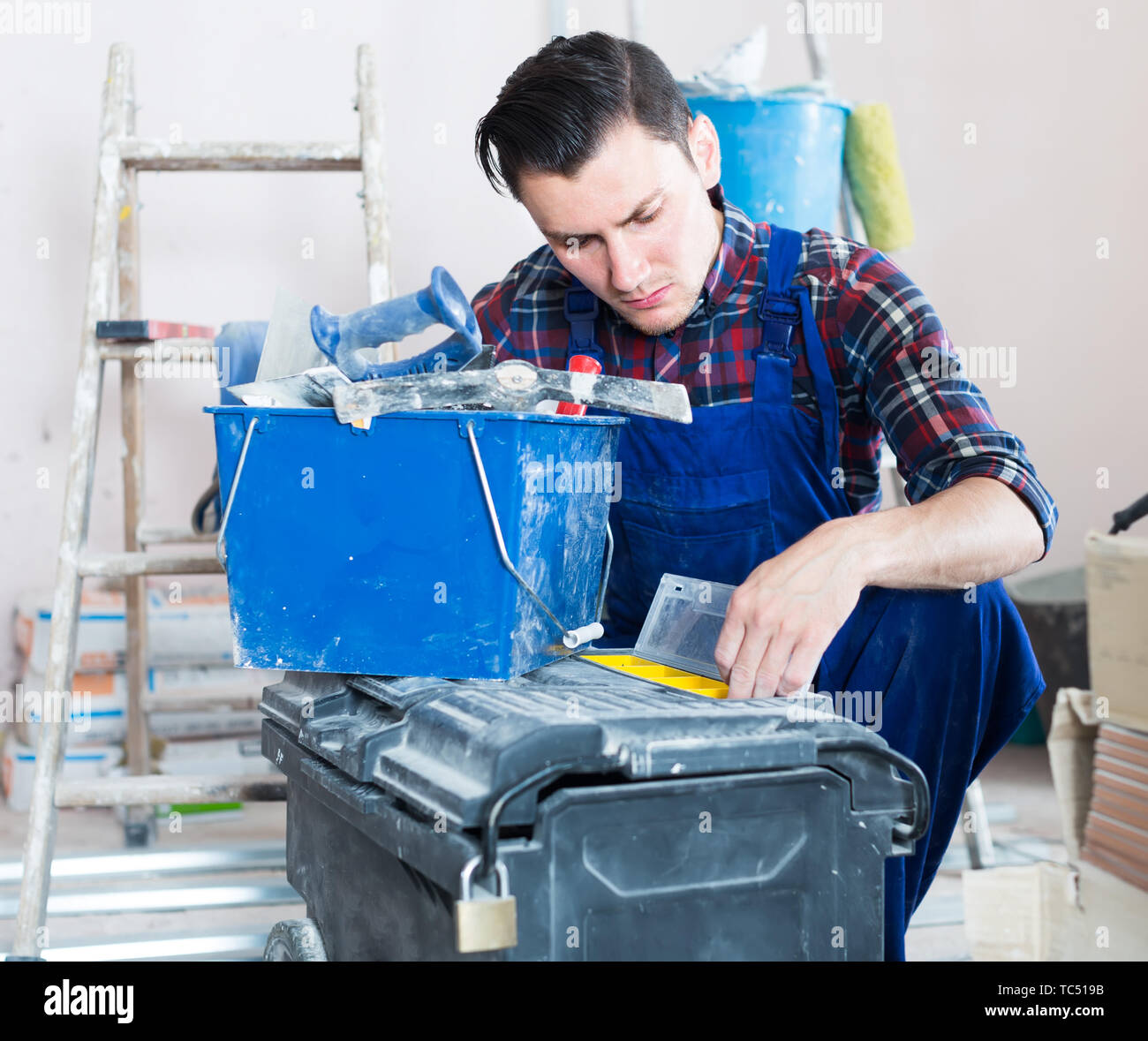 serious builder handyman choosing necessary tool in toolbox Stock Photo