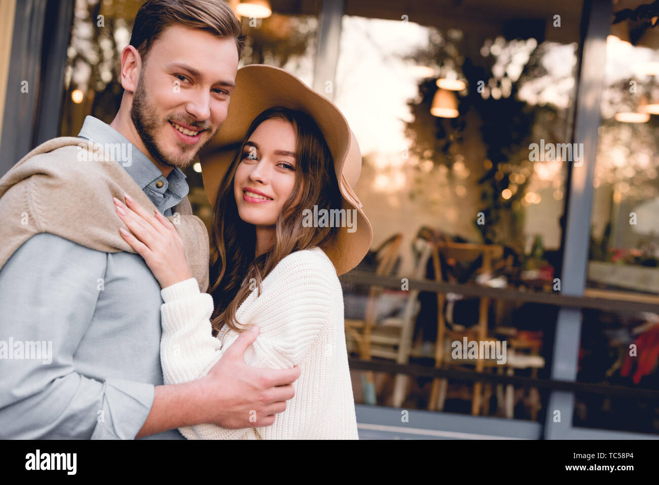 cheerful young woman in hat hugging handsome and happy boyfriend Stock ...