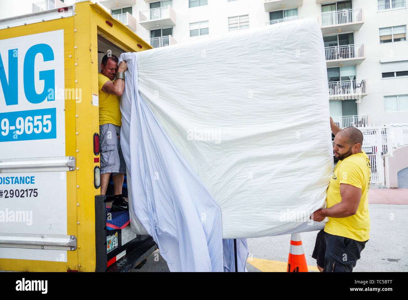 Miami Beach Florida,moving van company,movers,king size mattress,Hispanic man men male,employee working job,teamwork,lifting,loading,FL190228078 Stock Photo