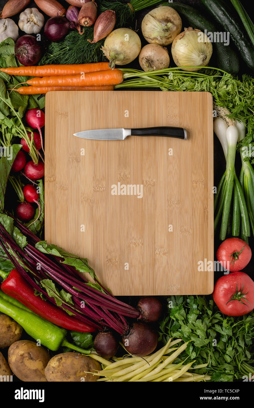 Small Kitchen Knife on Wood Cutting Board with Fresh Vegetables. Vegan Raw Food. Healthy Eating Concept. Stock Photo