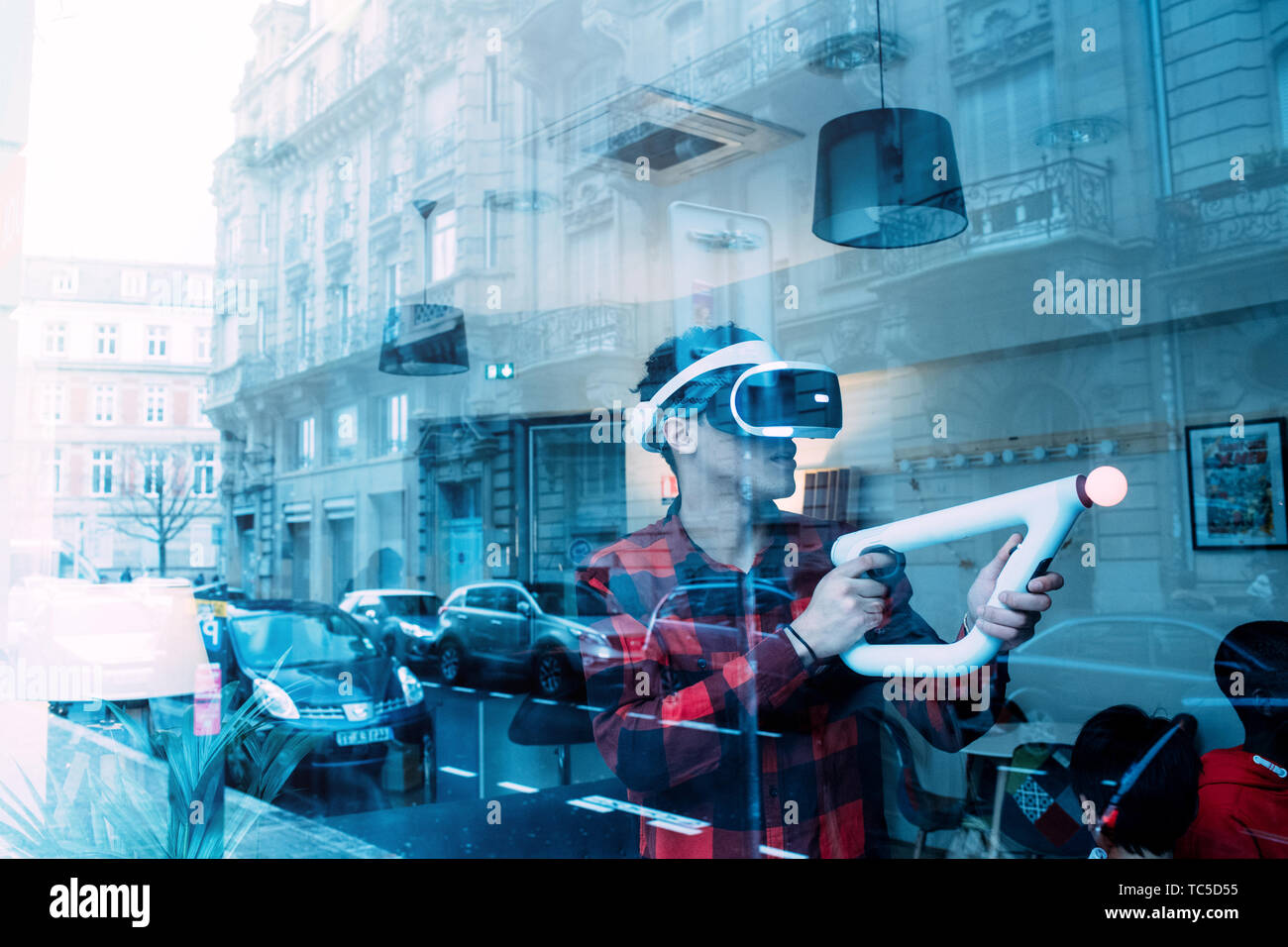 Strasbourg, France - Dec 27, 2017: Man playing inside free game zone with VR  set and Precise Aiming for PlayStationVR Aim Controller - city reflection  in shwocase window Stock Photo - Alamy