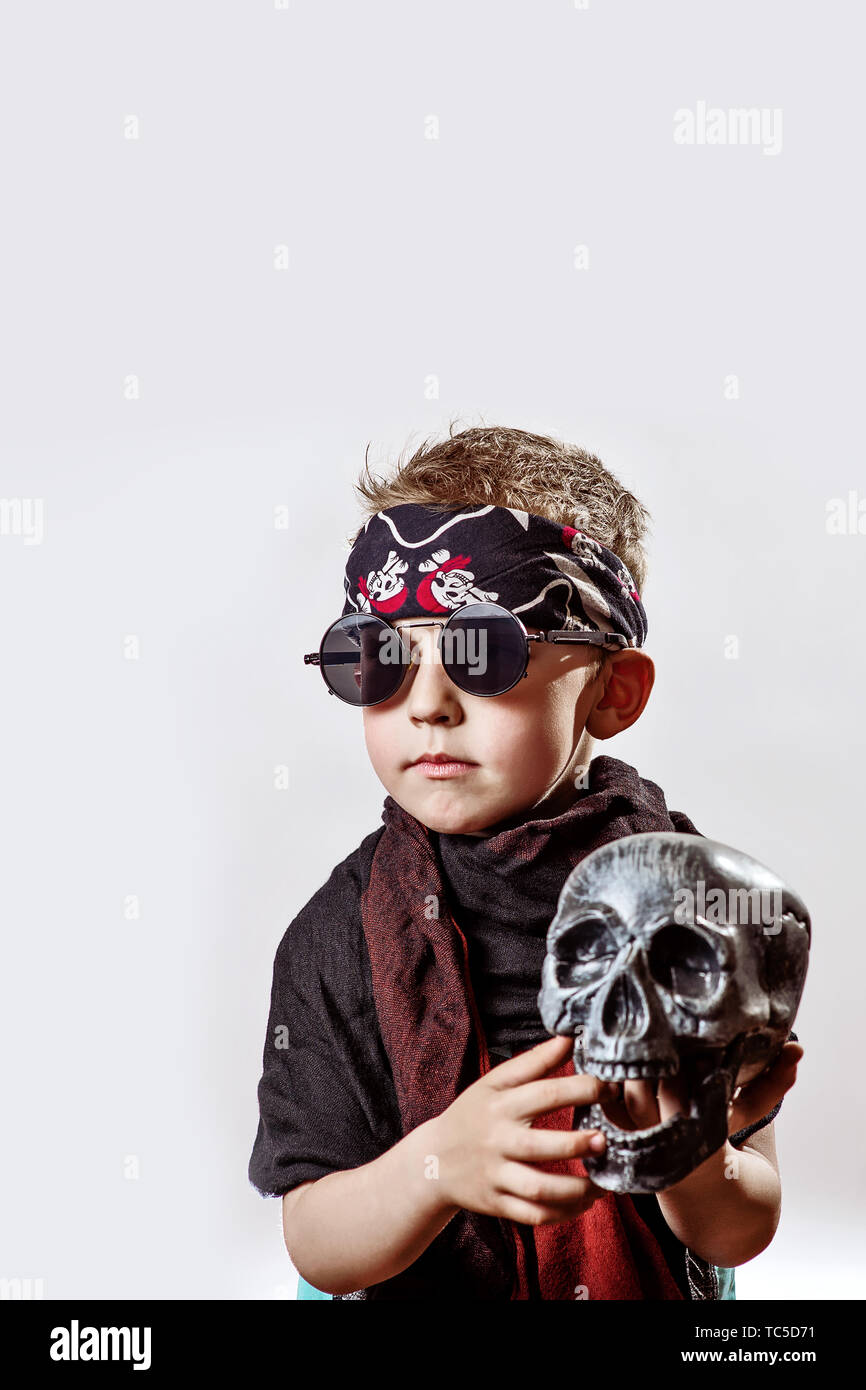 boy rocker in black glasses, scarf, bandana and with a skull in his hands  on a light background Stock Photo - Alamy