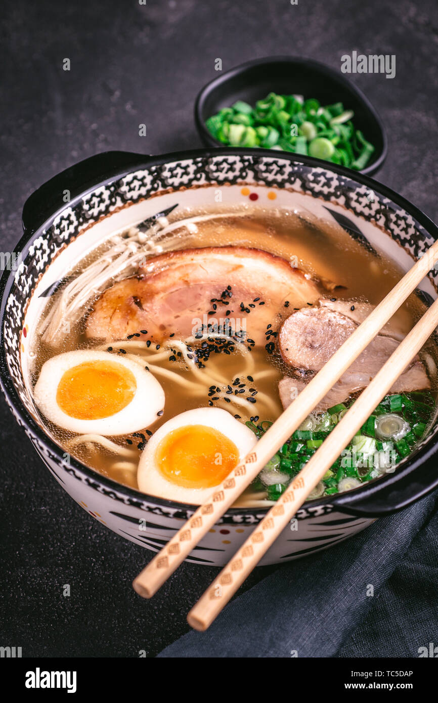 Udon Noodles in Japanese Ramen Soup with Pork, Eggs and Scallion on Dark Background Stock Photo