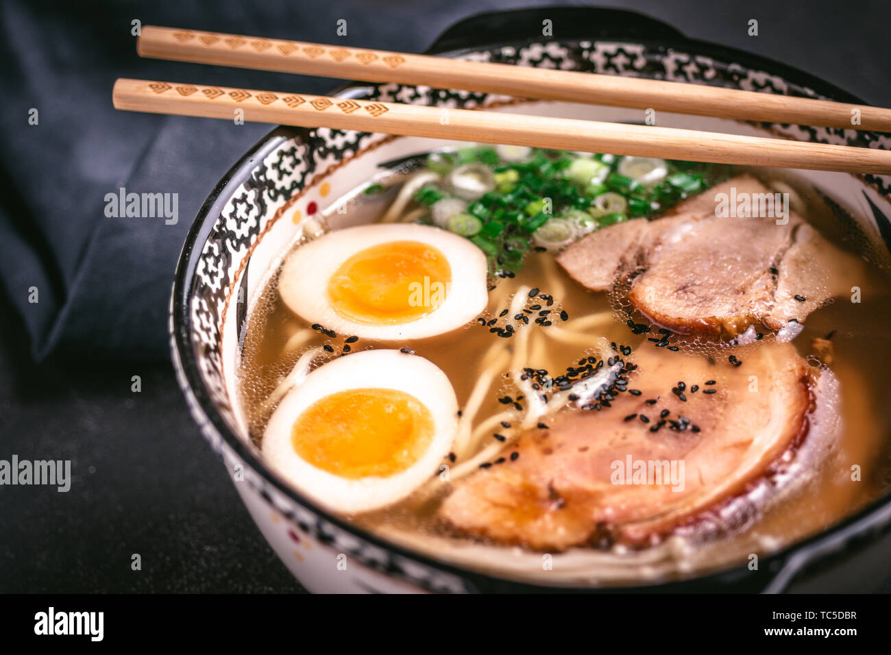 Udon Noodles in Japanese Ramen Soup with Pork, Eggs and Scallion on Dark Background Stock Photo
