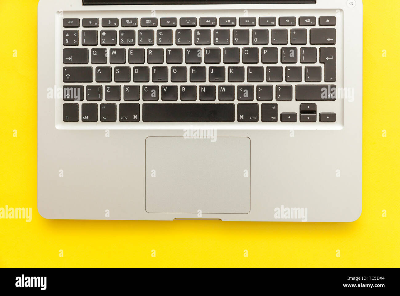 Keyboard laptop computer isolated on yellow desk background. Modern Information technology and sofware advances. Freelance home office programmer or d Stock Photo