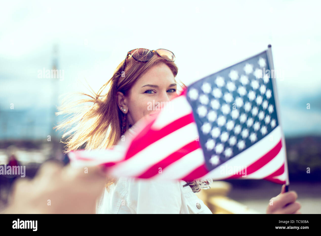 Happy young patriot modern urban woman holding USA flag portrait, depth of field, selective focus Stock Photo