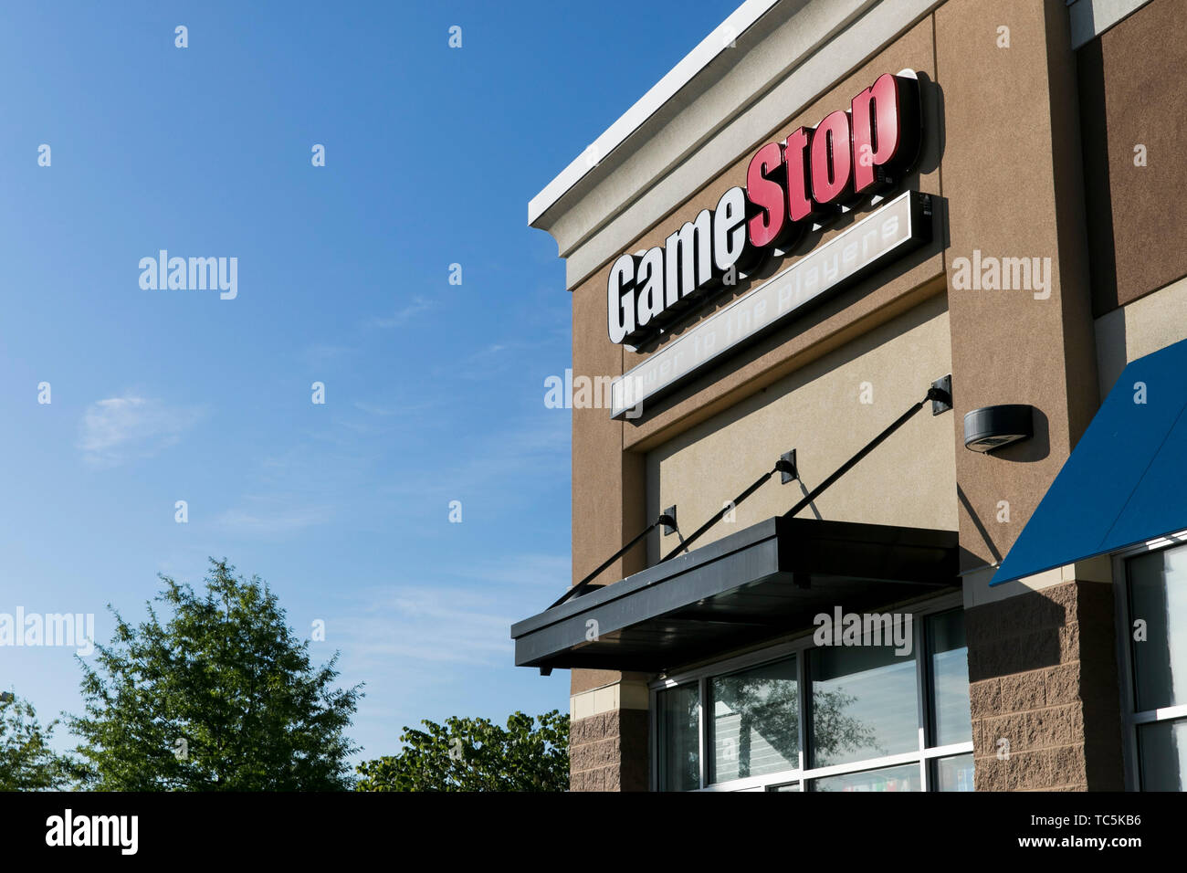 A logo sign outside of a GameStop retail store location in Martinsburg