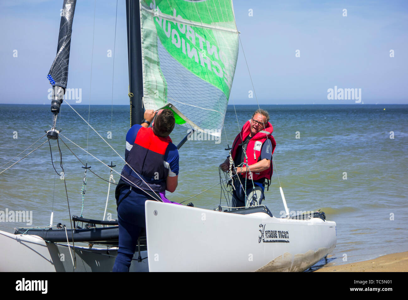 Two sailors preparing Hobie Cat, small sailing catamaran on the beach
