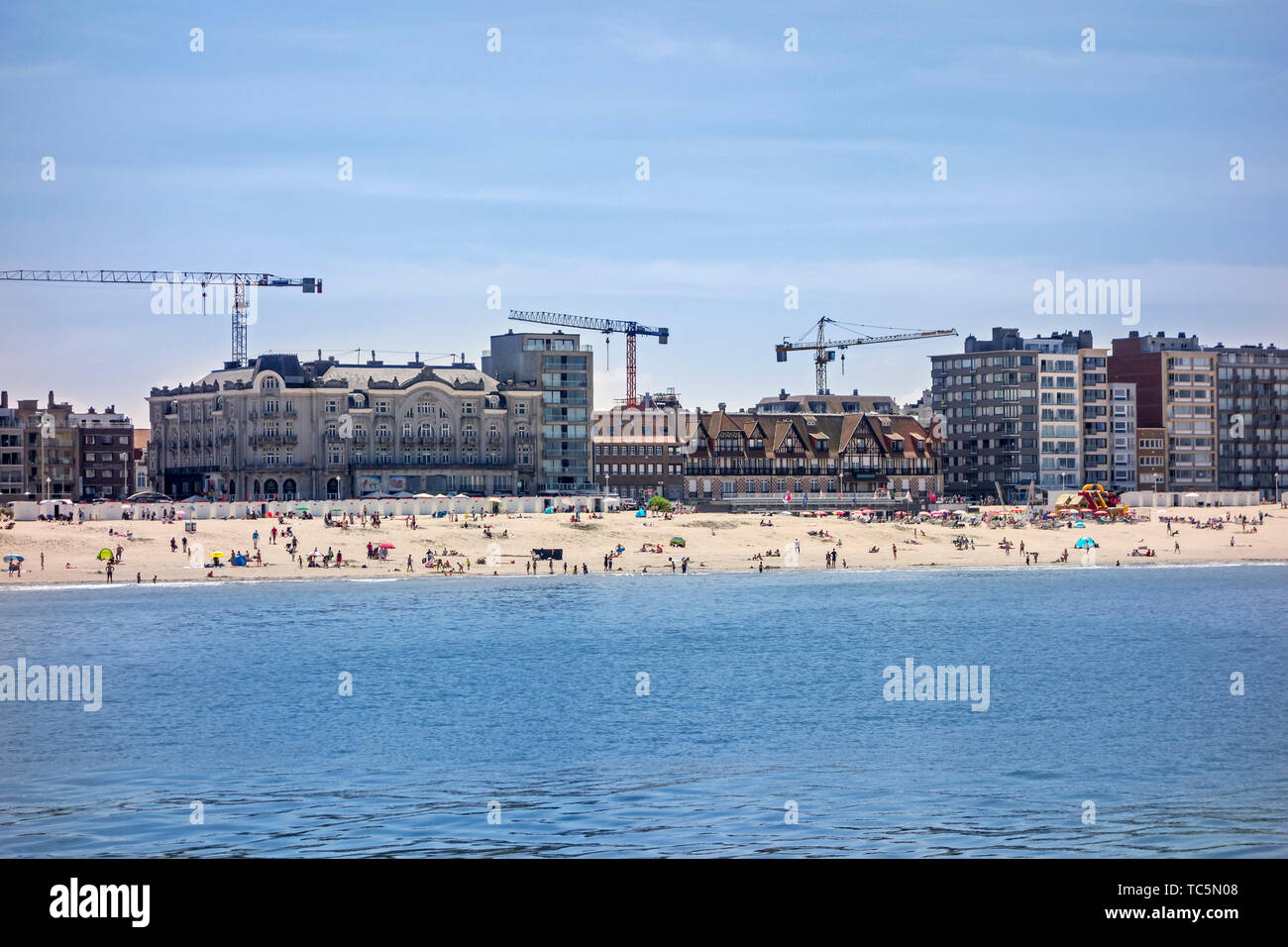 Tourists on the beach and flats and apartments being built at Nieuport / Nieuwpoort, seaside resort along the North Sea coast, West Flanders, Belgium Stock Photo