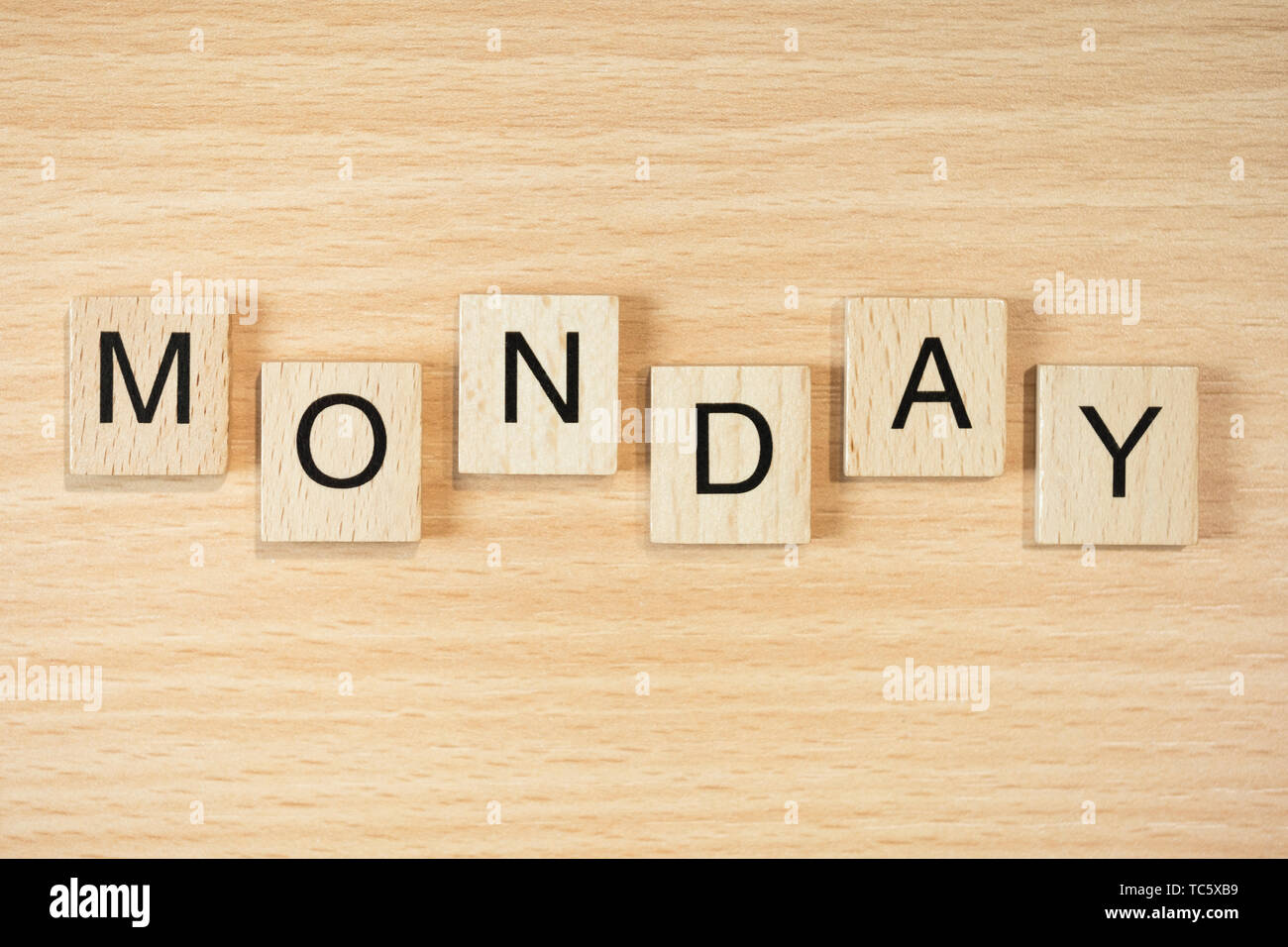 The word Monday, spelt out using wooden tiles on a wood effect background. Stock Photo