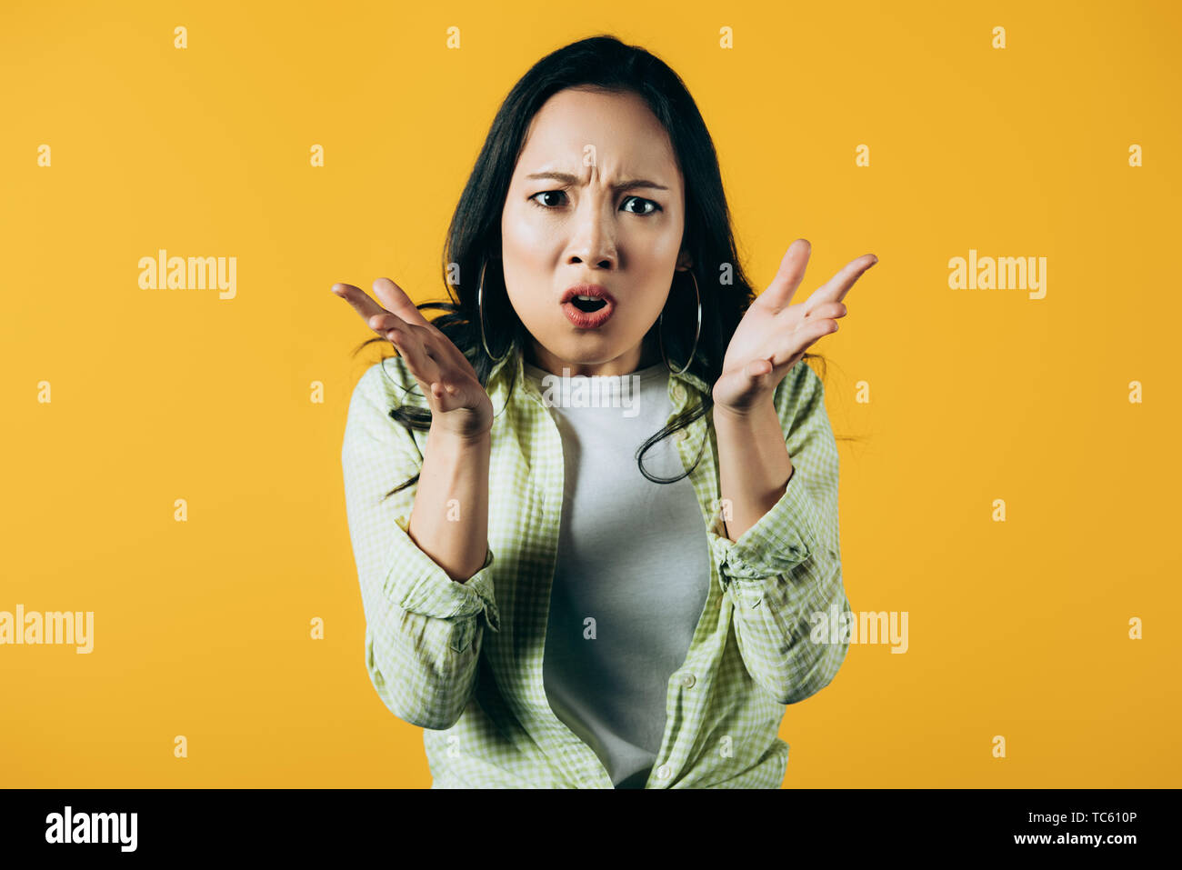 beautiful angry asian woman gesturing isolated on yellow Stock Photo ...