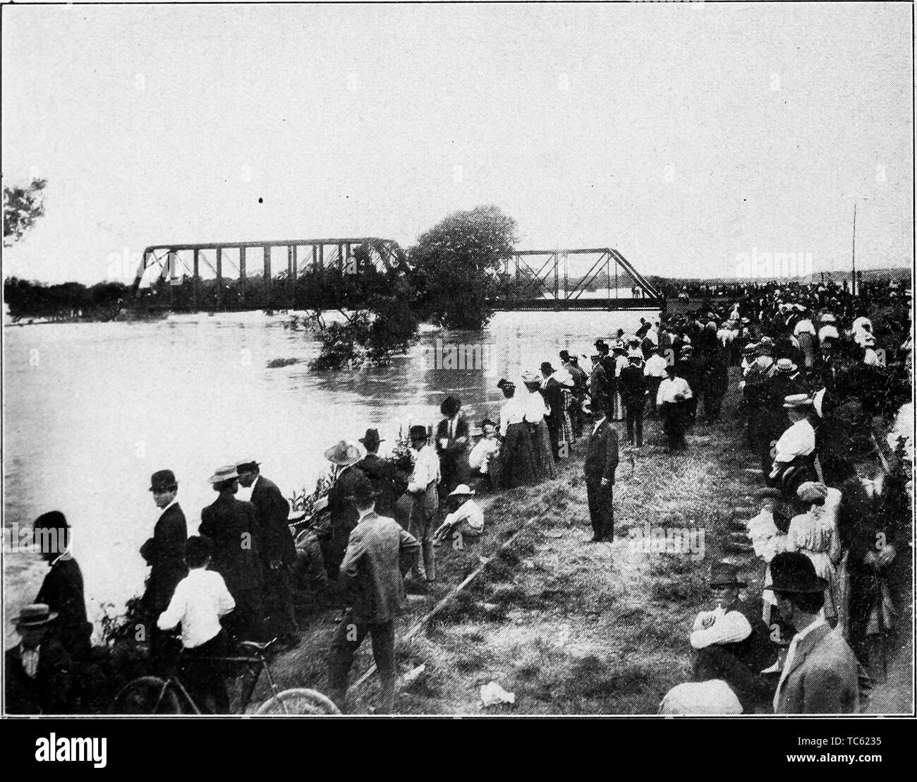 Photograph of a crowd of people gathered by the Trinity River at flood time, Dallas, Texas, from the book 'Book of Texas' by Harry Yandell Benedict and John A. Lomax, 1916. Courtesy Internet Archive. () Stock Photo